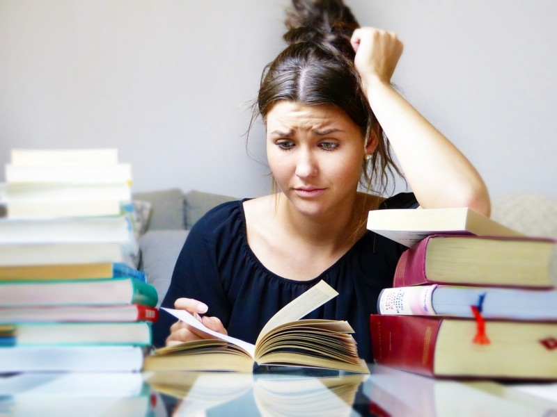 Women frazzled by a pile of books